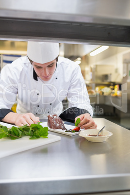 Chef putting mint leaf with cake