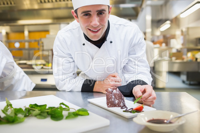 Smiling chef putting mint with his dessert