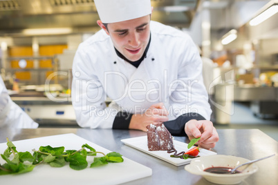 Cheerful chef putting mint with his dessert