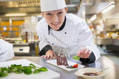 Smiling chef putting mint with her dessert