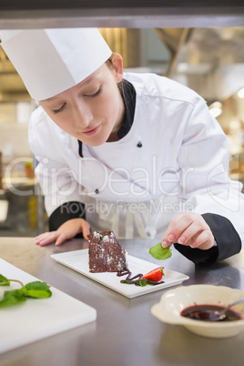 Female chef putting mint with cake Female chef putting mint with cake