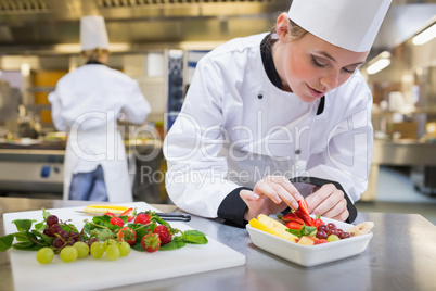 Chef putting a strawberry in the fruit salad