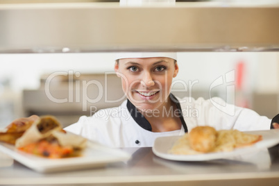 Chef handing dinner plates through order station