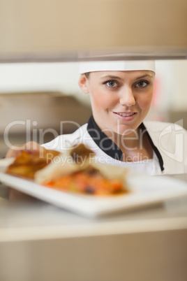Chef handing plate through order station