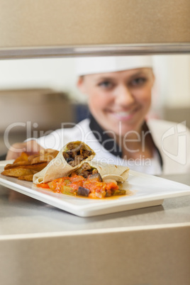 Cheerful chef giving plate through order station