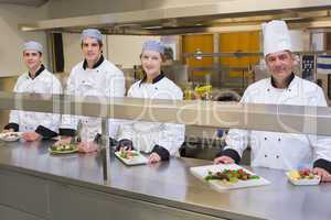 Four smiling Chef's with their dishes