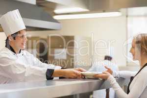 Chef giving a plate to the waitress