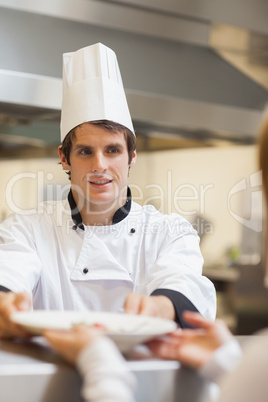 Chef passing plate to waitress