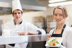 Waitress holding salmon dish smiling with chef