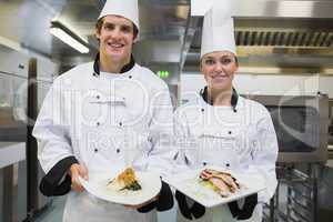 Two smiling Chef's showing plates