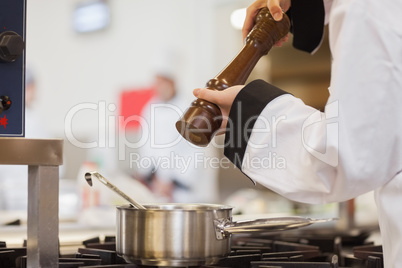 Chef adding pepper to soup