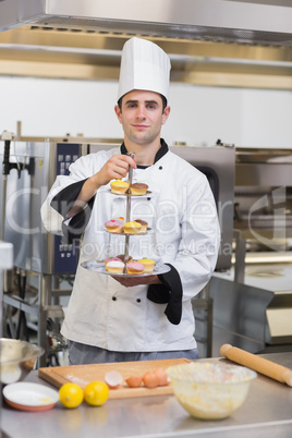 Pastry chef holding tiered cake tray