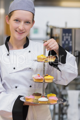 Smiling chef holding tiered cake tray