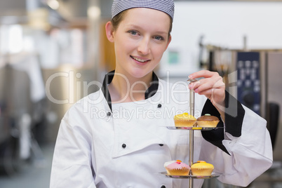Happy chef holding tiered cake tray