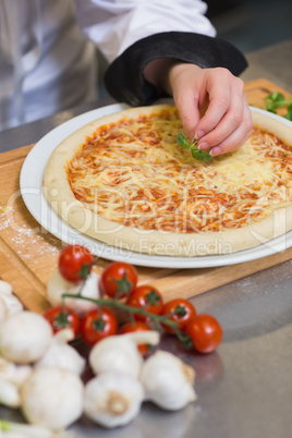 Pizza being garnished with basil leaf