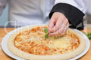 Basil leaf being put on pizza