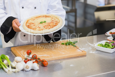 Chef holding up pizza