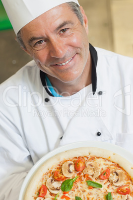 Smiling chef holding a pizza