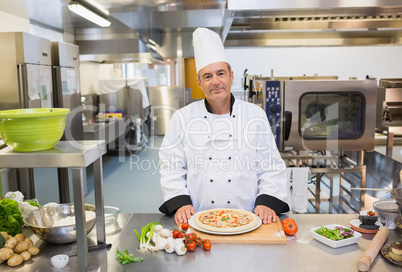 Chef standing in the kitchen with pizza