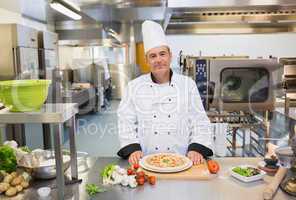 Chef standing in the kitchen with pizza
