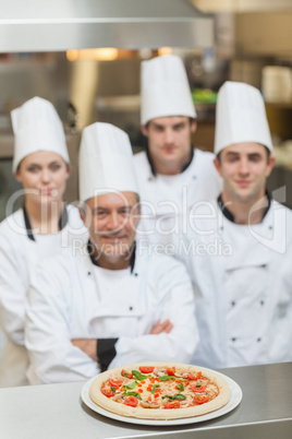 Pizza on the counter with team of Chef's behind