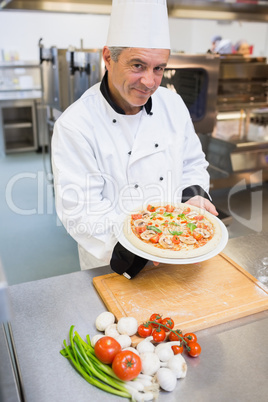 Cheerful man presenting a pizza