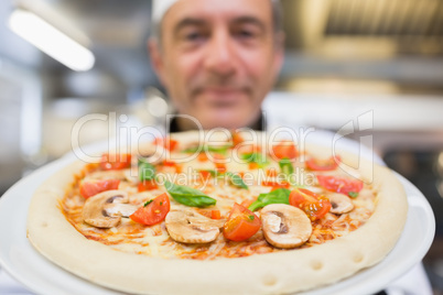 Chef holding pizza up