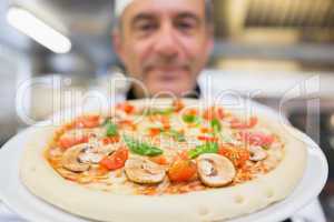 Chef holding pizza up