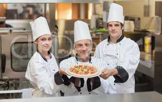 Three Chef's holding a pizza