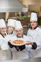 Four Chef's holding a pizza