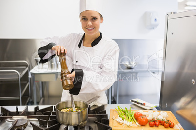 Chef spicing soup and smiling