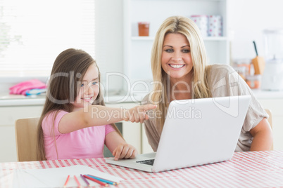 Daughter pointing at laptop with mother