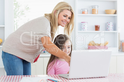 Mother pointing at laptop with daughter