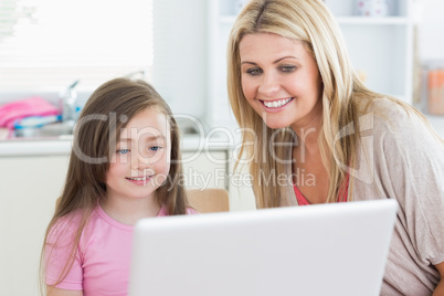 Woman and girl looking at the laptop monitor
