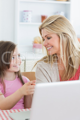 Daughter pointing at laptop with mother