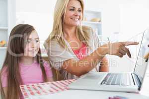 Mother pointing something out on laptop for daughter