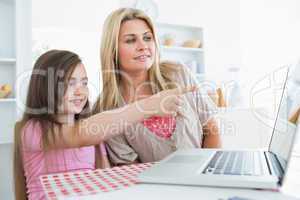 Child pointing something out on laptop to mother