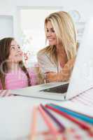 Woman smiling at her daughter by the laptop