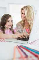 Little girl typing with mother smiling