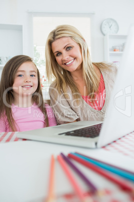 Mother and girl are smiling at the kitchen