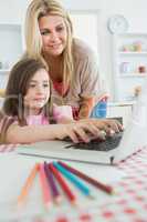 Woman standing looking at Daughter typing