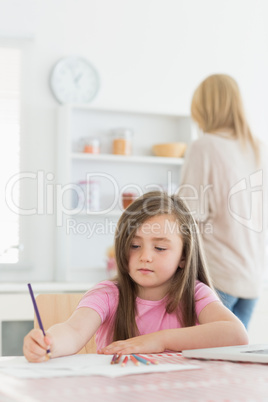 Girl sitting at the table drawing in kitchen