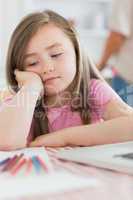 Girl sitting looking bored with paper and colouring pencils