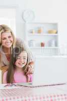 Laughing mother and girl looking at laptop