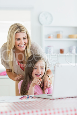Mother and child laughing at laptop with child pointing