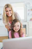 Woman and daughter smiling at the laptop