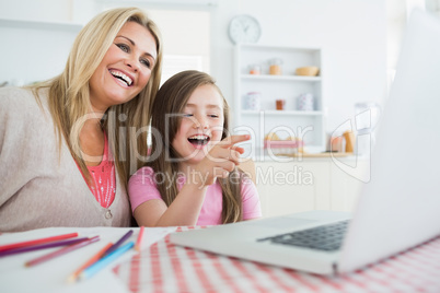 Woman and child sitting at the kitchen table laughing