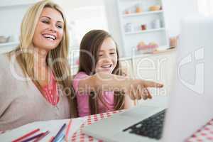 Little girl and mother laughing at laptop