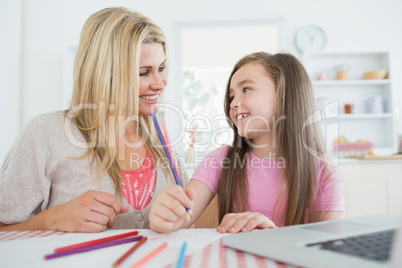 Woman and daughter smiling at each other and drawing