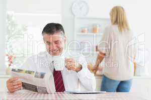 Man smiling while reading newspaper before work